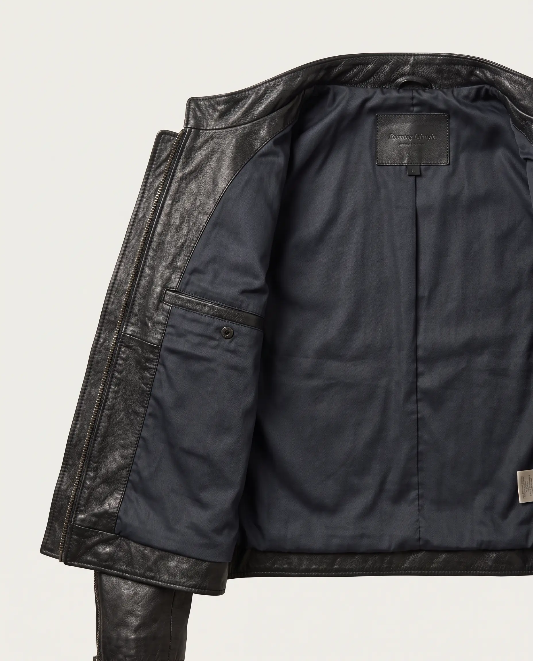 Interior view of men's black café racer leather jacket showing dark navy breathable twill lining, snap-button security breast pocket, branded leather neck patch, and interior zipper facing on a plain studio background – Roaming Lifestyle
