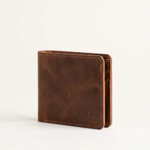 Handcrafted closed tobacco brown full-grain leather bifold wallet with contrast stitching and debossed mountain crest logo on a plain studio background – Roaming Lifestyle