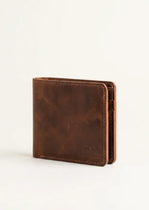 Handcrafted closed tobacco brown full-grain leather bifold wallet with contrast stitching and debossed mountain crest logo on a plain studio background – Roaming Lifestyle